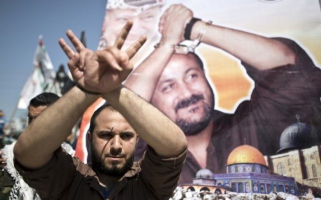 Un Palestinien prend la pose devant une affiche du leader du Fatah actuellement en prison, Marwan Barghouthi, au cours d'une manifestation pour le Jour des Palestiniens emprisonnés, à Gaza Ville, le 17 avril 2016. (Crédit : Mahmud Hams/AFP)