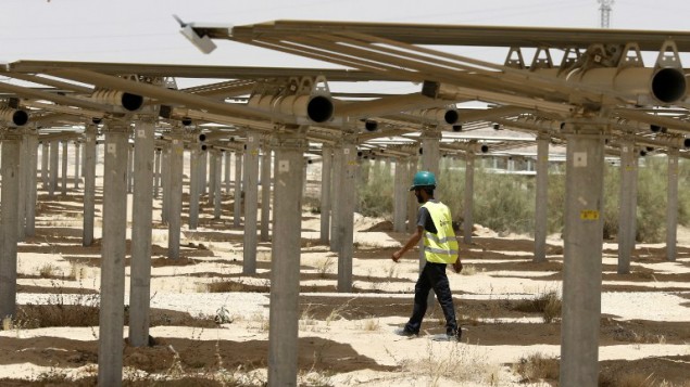 Un ouvrier passe sous les 55 000 miroirs redirigeant la lumière vers la tour solaire Ashalim, dans le désert du Néguev, le 26 mai 2016. (Crédit : Jack Guez/AFP)