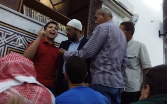 Abd Al-Aziz Al-Saifi, enfant autoproclamé prêcheur, pendant une de ses diatribes contre Israël dans une mosquée de Jordanie, alors que plusieurs hommes essaient de le persuader de se taire. (Crédit : capture d'écran YouTube)