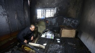 Un policier palestinien inspecte les dommages dans la maison incendiée d'un témoin clé au procès pour incendie criminel et meurtre de deux extrémistes juifs après une attaque de juillet 2015 à Duma, qui a fait trois morts palestiniens, un bébé et ses parents, à Duma, en Cisjordanie, le 20 mars 2016. (Crédit : AFP/Jaafar Ashtiyeh)