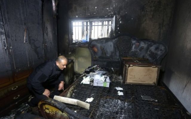 Un policier palestinien inspecte les dégâts à l'intérieur d'une maison incendiée appartenant à un témoin clé d'un incendie criminel perpétré par des extrémistes juifs qui ont tué une famille palestinienne, dans le village de Douma, en Cisjordanie, après l'incendie qui a éclaté dans la maison aux premières heures du 20 mars 2016. (AFP/Jaafar Ashtiyeh)