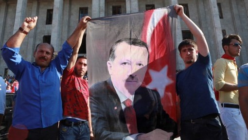 Des partisans du président turc Recep Tayyip Erdogan tiennent une bannière avec son portrait pendant un rassemblement devant le parlement turc, réuni en session extraordinaire à la suite d'une tentative de coup d'Etat, à Ankara, le 16 juillet 2016. (Crédit : AFP/Adem Altan)