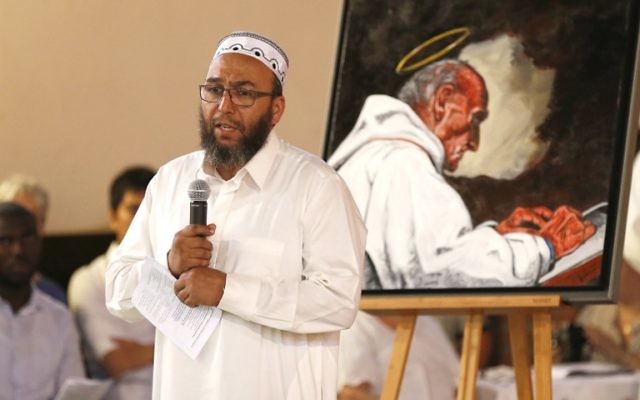 L'imam d'Oissel Abdellatif Hmito prononce un discours près d'un portrait du père Jacques Hamel, assassiné pendant une attaque terroriste, pendant une veillée en l'église Sainte-Thérèse de Saint-Etienne du Rouvray, le 30 juillet 2016. (Crédit : AFP/Charly Triballeau)