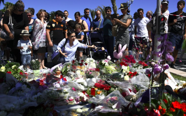 Les gens déposent des fleurs dans les rues de Nice pour rendre hommage aux victimes le lendemain de l'attaque, le 15 juillet 2016. (Crédit : AFP/Anne-Christine Poujoulat)