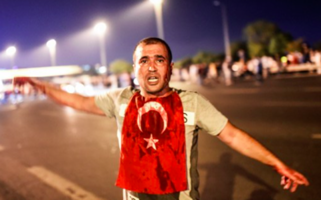 Un homme couvert de sang se trouve près du pont du Bosphore au milieu d'affrontements militaires turcs avec des personnes à l'entrée du pont à Istanbul le 16 juillet 2016. (Crédit : AFP / Bulent KILIC)