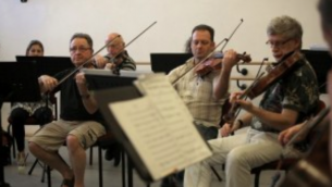 L'Israël Camerata Jerusalem Orchestra jouent avec des "Violins de l'espoir",le 13 juillet 2016. (Crédit : AFP / MENAHEM KAHANA)