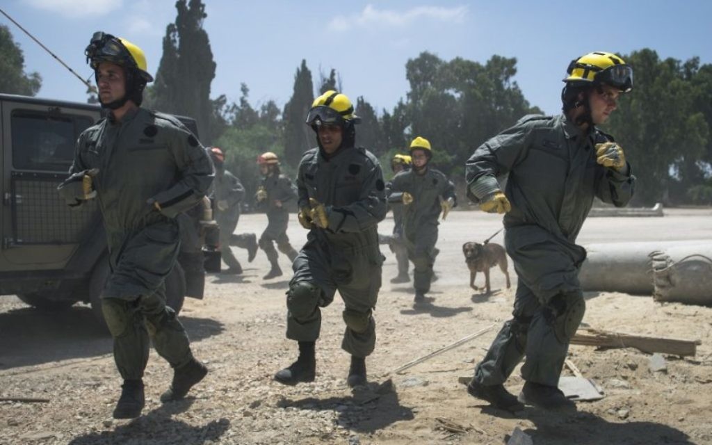 Des soldats des unités de recherche et sauvetage du Commandement de la Défense passive de l'armée israélienne courent sur la scène d'une fausse frappe de roquette pendant un exercice à grande échelle, à Zikim, près de la frontière de la bande de Gaza, le 3 juillet 2016. (Crédit : unité des porte-paroles de l'armée israélienne)