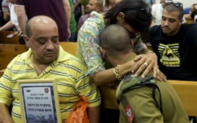 Le soldat de l'armée israélienne Elor Azaria, qui est jugé pour avoir abattu un attaquant palestinien désarmé, dans les bras d'une personne le soutenant au tribunal militaire de Jaffa, le 5 juillet 2016 (Crédit : Flash90)
