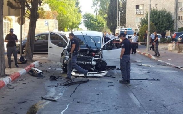 La police inspecte une voiture endommagée par une explosion, rue Mapu, dans le centre de Jérusalem, le 27 juillet 2016. (Crédit : police israélienne)
