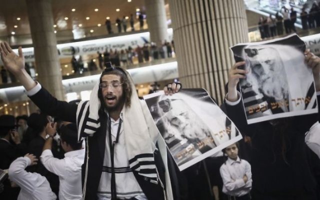 Des Juifs ultra-orthodoxes se rassemblent pour prier lors d'une manifestation de soutien au rabbin Eliezer Berland avant son arrivée à l'aéroport Ben Gourion à Tel Aviv, le 19 juillet 2016. (Crédit photo : Yonatan Sindel/Flash90)