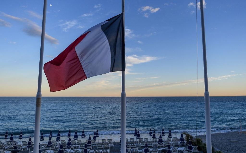 Drapeau français en berne devant une plage vide de la Promenade des Anglais à Nice, au lendemain d'un attentat qui a fait 84 morts, le 15 juillet 2016. (Crédit : David Ramos/Getty Images via JTA)