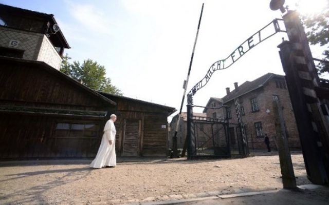 Le pape François à l’entrée principale de l’ancien camp d’extermination nazi d’Auschwitz-Birkenau, qui porte les mots "Arbeit macht frei" ("le travail rend libre"), à Oswiecim, en Pologne, le 29 juillet 2016. (Crédit : Filippo Monteforte/AFP)