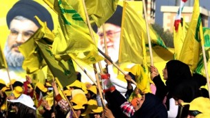 Des femmes agitent des drapeaux libanais ou du groupe terroriste chiite du Hezbollah devant des portraits du guide suprême iranien, l'ayatollah Ali Khamenei (à droite) et le chef du Hezbollah Hassan Nasrallah, pendant un discours de ce dernier commémorant les dix ans de la deuxième guerre du Liban, à Bint Jbeil, le 13 août 2016. (Crédit : AFP/Mahmoud Zayyat)