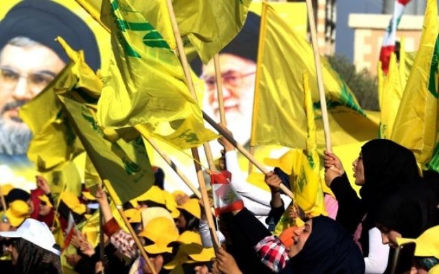 Des femmes agitent des drapeaux libanais ou du groupe terroriste chiite du Hezbollah devant des portraits du guide suprême iranien, l'ayatollah Ali Khamenei (à droite) et le chef du Hezbollah Hassan Nasrallah, pendant un discours de ce dernier commémorant les dix ans de la deuxième guerre du Liban, à Bint Jbeil, le 13 août 2016. (Crédit : AFP/Mahmoud Zayyat)
