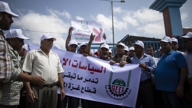 Des hommes d'affaires et des marchands palestiniens manifestant pour protester contre la suspension par Israël de leurs permis de voyage les autorisant à se rendre en Israël et en Cisjordanie, à Beit Hanun, près du poste-frontière d'Erez, dans le nord de la bande de Gaza, le 15 août 2016. (Crédit : AFP/Mahmud Hams)
