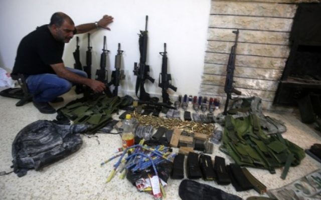 Un membre des forces de l'ordre palestinienne présente des armes que la police a trouvé pendant la recherche de deux hommes armés, toujours en fuite, au poste de police de Naplouse en Cisjordanie, le 21 août 2016. (Crédit : AFP/Jaafar Ashtiyeh)