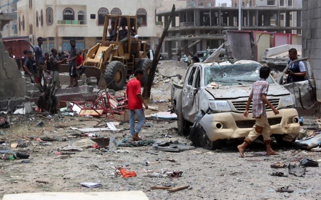 Des Yéménites inspectent le site d'un attentat à la voiture suicide revendiqué par le groupe de l'Etat islamique le 29 août 2016 au centre de recrutement de l'armée dans la ville yéménite d'Aden. (Crédit : AFP/Saleh Al-Obeidi)