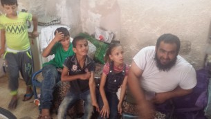 Anwar Burqan, une enfant palestinienne de 8 ans dont la bicyclette avait été détruite par deux gardes-frontières, pose pour une photo avec son père Amer, à droite, et trois de ses frères et sœurs dans leur maison de famille à Hébron, le 17 août 2016. (Crédit : Lonny Baskin)