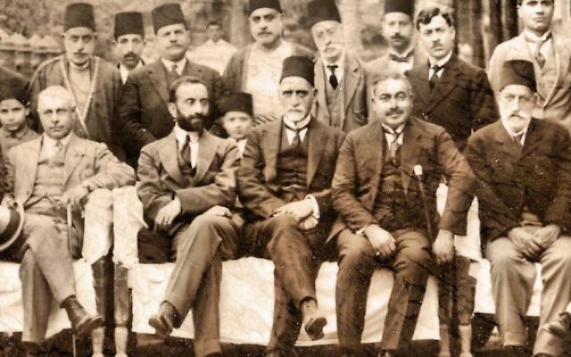 Sir Sassoon Eskell (au centre, avec un fez) est assis juste à côté du roi Faisal Ier d'Irak (avec une barbe noire) à Bagdad, dans les années 1920. (Crédit : WikiCommons)