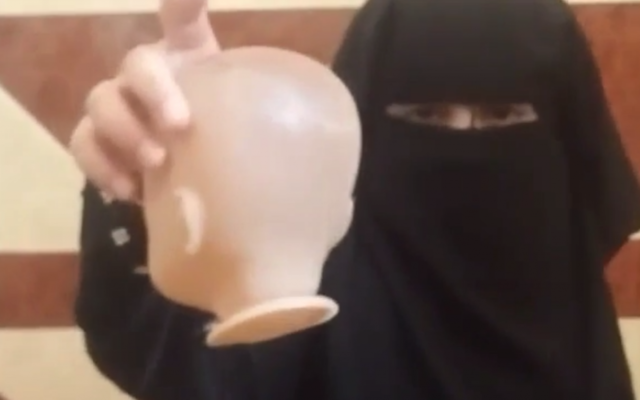 Un enfant tient la tête d'une poupée récemment décapitée dans une vidéo publiée en ligne par un sympathisant de l'Etat islamique, le 4 août 2016 (Crédit : Capture d'écran MEMRI)