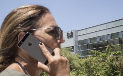 Une Israélienne utilise son iPhone face au bâtiment abritant le firme de cyber-sécurité israélienne NSO Group, le 28 août 2016 à Herzliya. (Crédit : AFP Photo / Jack Guez)