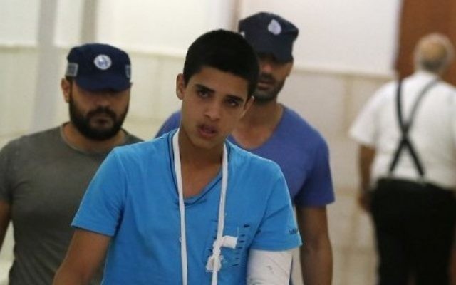 Ahmed Manasra (au premier plan), adolescent palestinien de 14 ans, a été jugé coupable de tentative de meurtre à l'encontre de deux jeunes Israéliens pendant une attaque au couteau en octobre 2015, à sa sortie du tribunal de Jérusalem, le 25 septembre 2016. (Crédit : Ahmad Gharabli/AFP)