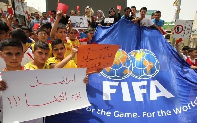De jeunes Palestiniens avec des cartons rouges et des pancartes "Israël en-dehors de la FIFA" pendant une manifestation contre la Fédération israélienne de football à Hébron, en Cisjordanie, le 28 mai 2015. (Crédit : AFP/Hazem Bader)