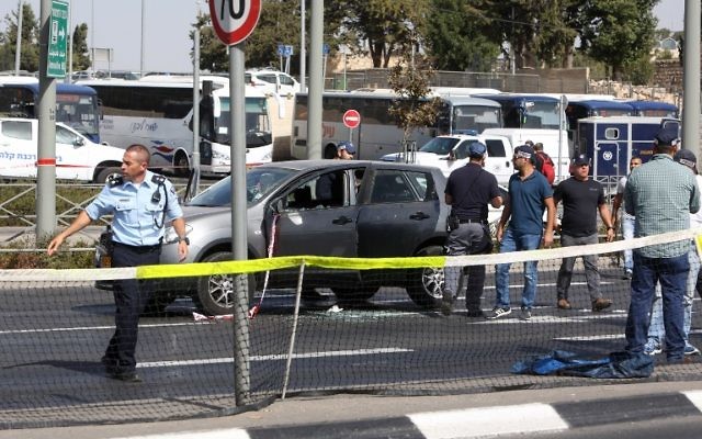 La police scientifique israélienne collecte des preuves dans la voiture appartenant à une victime après une attaque à main armée près du siège de la police à Jérusalem, le 9 octobre 2016. (Crédit : AFP/Menahem Kahana)