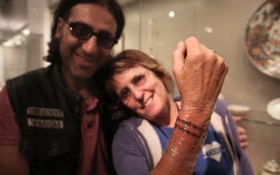 Kay Wilson montre une prière tatouée en hébreu sur son poignet, faite par le célèbre tatoueur Wassim Razzouk, un chrétien palestinien de la Vieille Ville de Jérusalem, dans le cadre d'une initiative visant à utiliser l'art pour guérir les blessures mentales et physiques dans une salle d'exposition d'art moderne dans le musée d'Israël à Jérusalem, le 20 octobre 2016. (Crédit : AFP / MENAHEM KAHANA)