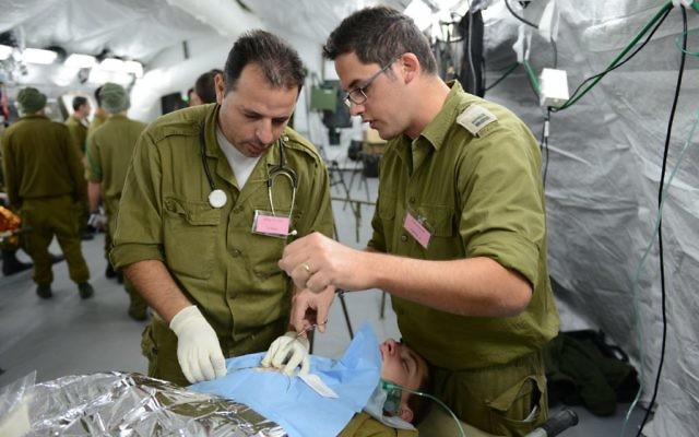 Deux médecins militaires israéliens réalisent une "chirurgie" pendant un exercice d'hôpital de campagne à Beit Naballah, dans le centre d'Israël, le 9 décembre 2013. (Crédit : unité des porte-paroles de l'armée israélienne)