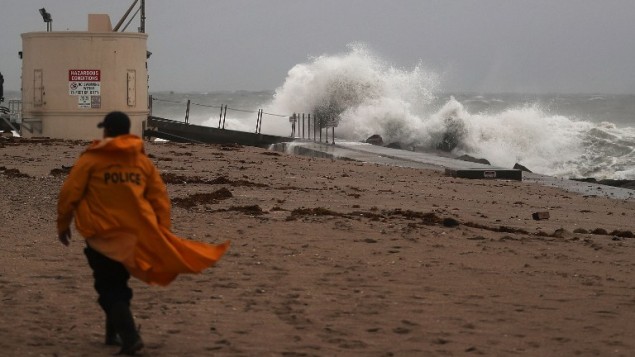 Un policier parcourt la plage tandis que les vagues s'écrasent sur la plage, avec l'arrivée de l'ouragan Matthew, à Singer Island, en Floride, le 6 octobre 2016. (Crédit : Joe Raedle/Getty Images/AFP)