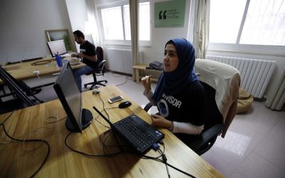 Des Palestiniens dans les bureaux de Red Crow, une start-up qui surveille les évènements sécuritaires et envoie des alertes en temps réel et des cartes à ses clients, à Ramallah, le 17 août 2016. (Crédit : AFP/Abbas Momani)