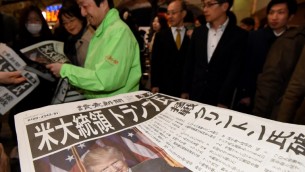 Un homme distribue des éditions supplémentaires des journaux annonçant la victoire de Donald Trump à l'élection présidentielle américaine à Tokyo, le 9 novembre 2016. (Crédit : AFP/Toru Yamanaka)