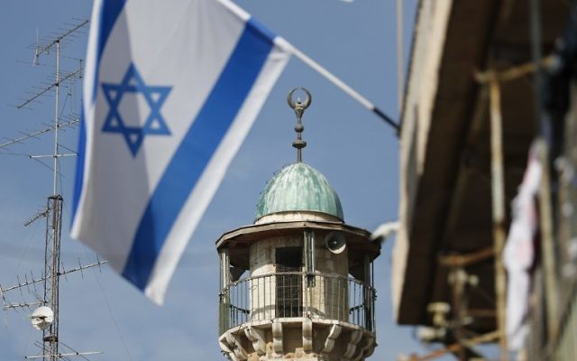 Un drapeau israélien devant un minaret d'une mosquée du quartier musulman de la Vieille Ville de Jérusalem, le 14 novembre 2016. (Crédit : Thomas Coex/AFP)