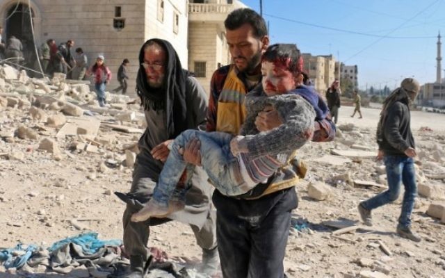 Un bénévole, membre des Casques blancs, transporte un enfant sauvé des décombres après un bombardement de la ville d'Alep, le 24 novembre 2016. (Crédit : Ameer Alhalbi/AFP)