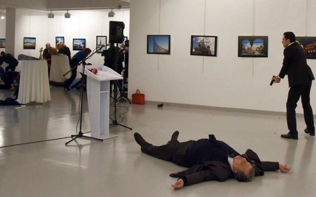 Andreï Karlov, l'ambassadeur de la Russie auprès de la Turquie, gît au sol près de son assassin, qui vise toujours le public d'une exposition à Ankara, le 19 décembre 2016. (Crédit : STRINGER/AFP)