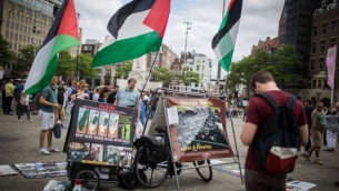 Des touristes israéliens devant un stand du BDS avec des photos et des drapeaux palestiniens, appelant à la "Palestine libre", à sur la place de Dam, au centre d'Amsterdam, en Hollande, le 24 juin 2016. (Crédit : Hadas Parush/Flash90)