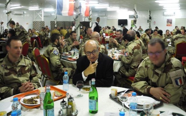 Le (vrai) ministre français de la Défense, Jean-Yves Le Drian, au centre, entourés des soldats de l'armée de l'air française sur une base militaire de Jordanie, le 31 décembre 2016. (Crédit : Valérie Leroux/AFP)