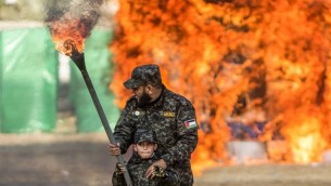 Un Palestinien aide un petit garçon à enflammer un drapeau israélien pendant la cérémonie de fin d'un programme de formation militaire du Hamas, à Gaza Ville, le 22 janvier 2017. (Crédit : Mahmud Hams/AFP)