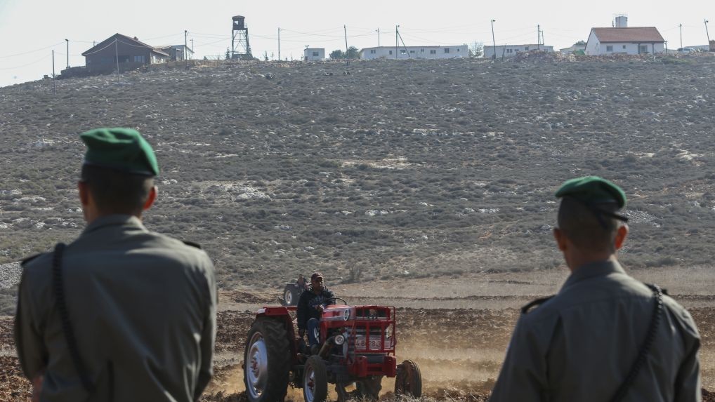 Les officiers de la police des frontières montant la garde pendant que les agriculteurs palestiniens utilisent des tracteurs pour travailler la terre dans le village de Qusra en Cisjordanie, avec l'avant-poste Esh Kodesh en arrière-plan, le 19 novembre 2013. (Crédit : Nati Shohat/Flash90)