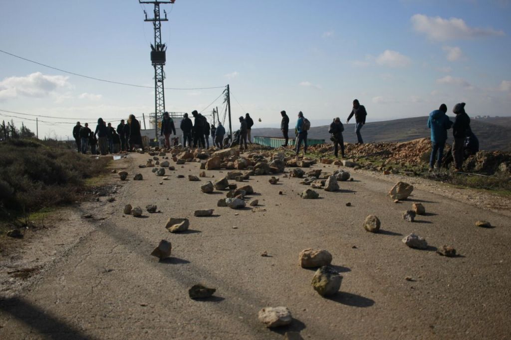 Des manifestants israéliens placent des rochers sur la route menant à l'avant-poste de Cisjordanie d'Amona, avant son démantèlement, le 1er février 2017. (Crédit : Judah Ari Gross/Times of Israël)