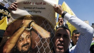 Un homme avec une photo du terroriste palestinien condamné Marwan Barghouthi pour demander sa libération pendant une manifestation de soutien aux détenus en grève de la faim à Hébron, en Cisjordanie, le 17 avril 2017. (Crédit : Hazem Bader/AFP)
