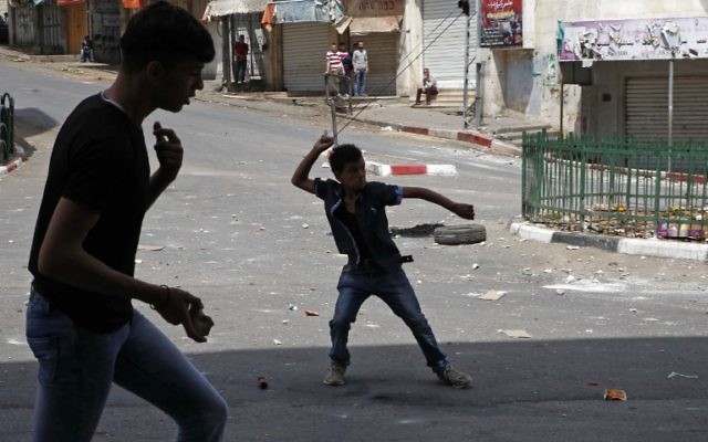 Des manifestants palestiniens jettent des pierres sur des soldats israéliens à Hébron, en Cisjordanie, le 27 avril 2017. Illustration. (Crédit : Hazem Bader/AFP)