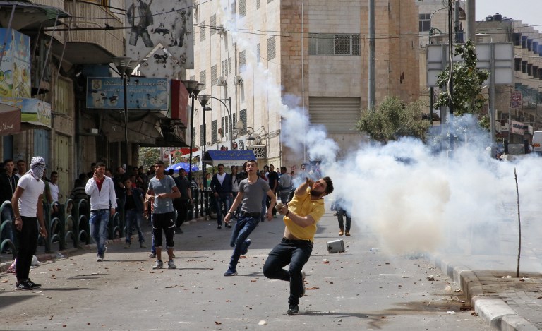 Des manifestants palestiniens jettent des pierres lors d'affrontements avec des soldats israéliens dans la ville de Hébron, en Cisjordanie, le 27 avril 2017/ (Crédit : Hazem Bader/AFP)