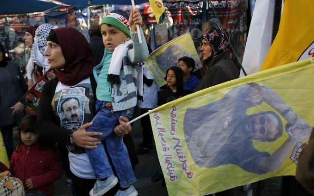 Manifestation de soutien aux prisonniers palestiniens en grève de la faim en Israël, à Ramallah, le 24 avril 2017.  Le drapeau porte un portrait de Marwan Barghouthi. (Crédit : Abbas Momani/AFP)