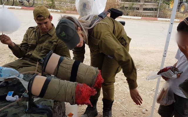 Des soldats de la brigade Etzion montrent une paire de fausses jambes amputées à un enfant de l'implantation de Tekoa pendant une exposition militaire pour Yom HaAtsmaout, le 2 mai 2017. (Crédit : autorisation)