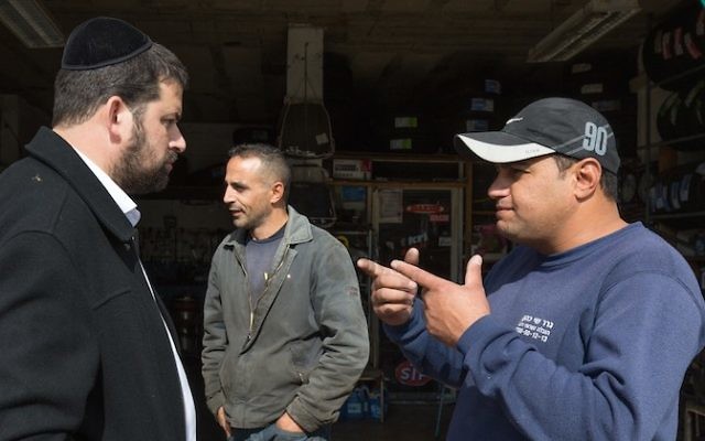 Un Juif ultra orthodoxe de l'implantation israélienne de Beitar Illit en train de parler à un Arabe à l'intersection de Hussan, en Cisjordanie, le 11 novembre 2015 (Crédit : Nati Shohat / Flash90