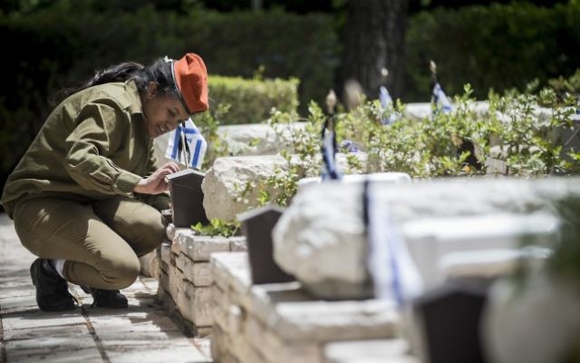 Une soldate israélienne allume des bougies près des tombes des soldats morts au combat au cimetière militaire du mont Herzl, à Jérusalem, le 30 avril 2017. (Crédit : Yonatan Sindel/Flash90)
