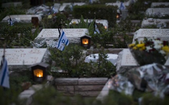Des bougies devant les tombes des soldats morts au combat au cimetière militaire du mont Herzl à Jérusalem, le 30 avril 2017. (Crédit : Yonatan Sindel/Flash90)