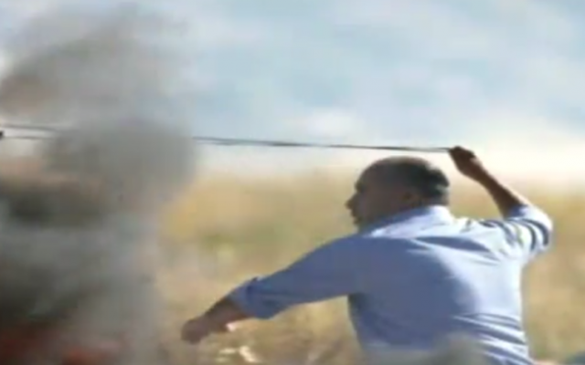 Jamal Hawil, député de l'Autorité palestinienne, jette des pierres contre des soldats israéliens pendant des affrontements près du carrefour Beit El, en Cisjordanie, le 13 mai 2017. (Crédit : capture d'écran Deuxième chaîne)